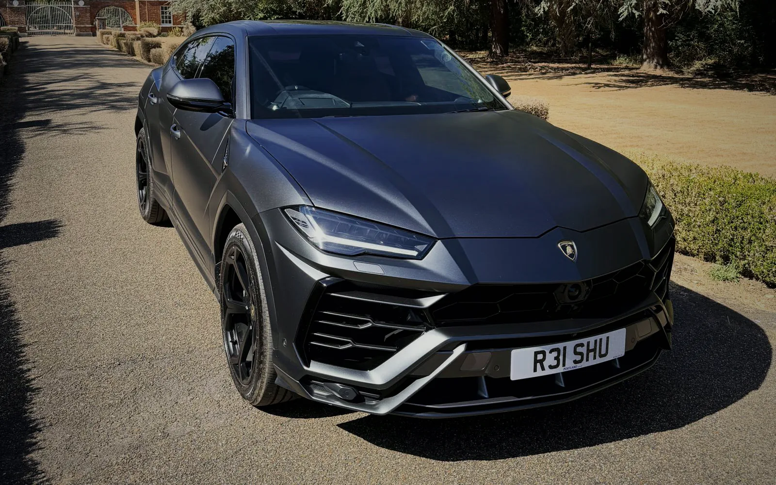 Front three-quarter view of the Lamborghini Urus on a gated estate driveway